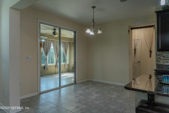 unfurnished dining area featuring light tile patterned floors, ceiling fan with notable chandelier, and baseboards