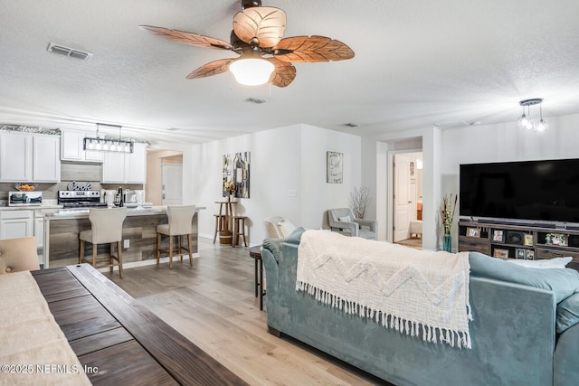 95170 Timberlake Dr, Fernandina Beach, FL 32034 - living room with a textured ceiling, ceiling fan, light wood-style flooring, and visible vents