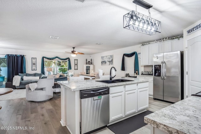 95170 Timberlake Dr, Fernandina Beach, FL 32034 - kitchen featuring a kitchen island with sink, white cabinetry, light countertops, appliances with stainless steel finishes, and decorative light fixtures