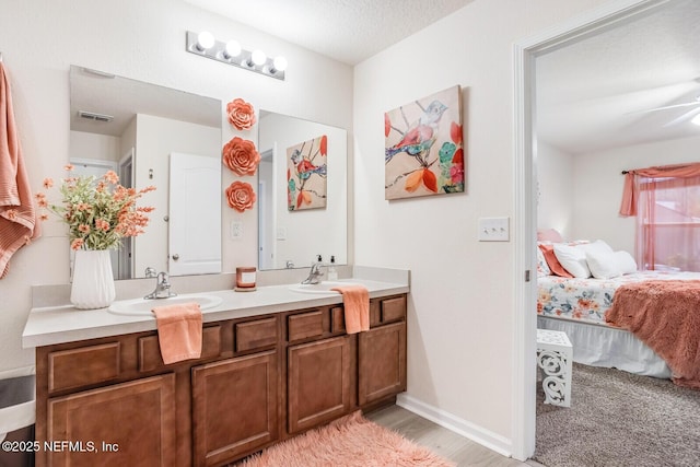 95170 Timberlake Dr, Fernandina Beach, FL 32034 - ensuite bathroom with double vanity, visible vents, connected bathroom, a textured ceiling, and a sink