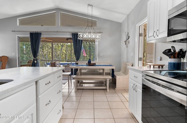 kitchen featuring stainless steel appliances, lofted ceiling, light tile patterned flooring, and white cabinetry