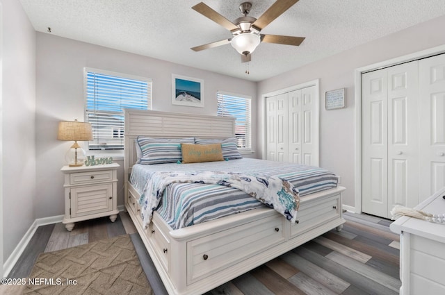 bedroom with a textured ceiling, baseboards, two closets, and wood finished floors