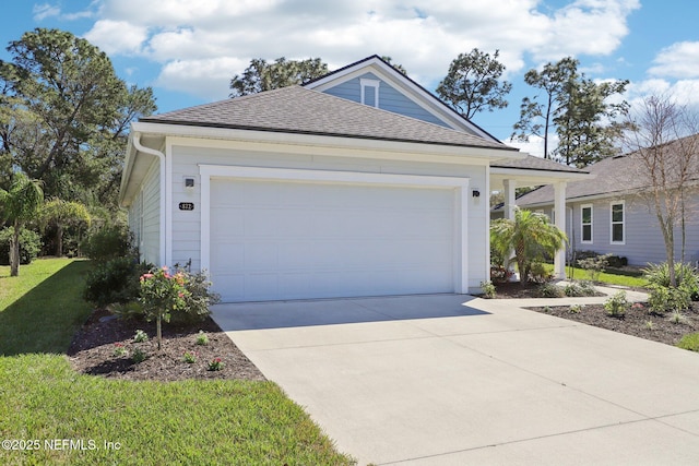 view of front of property featuring driveway, roof with shingles, a garage, and a front yard