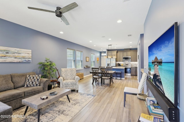 living area with light wood finished floors, ceiling fan, baseboards, and recessed lighting