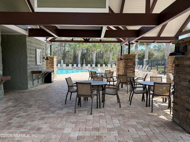 view of patio featuring a community pool, fence, outdoor dining area, and a gazebo