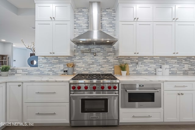 kitchen featuring white cabinets, wall chimney exhaust hood, tasteful backsplash, and stainless steel appliances