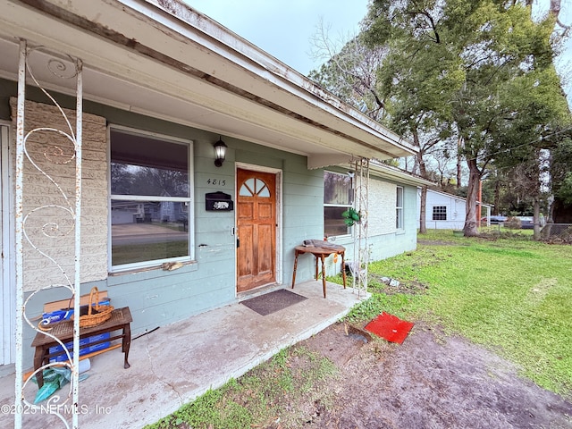 view of exterior entry featuring a lawn