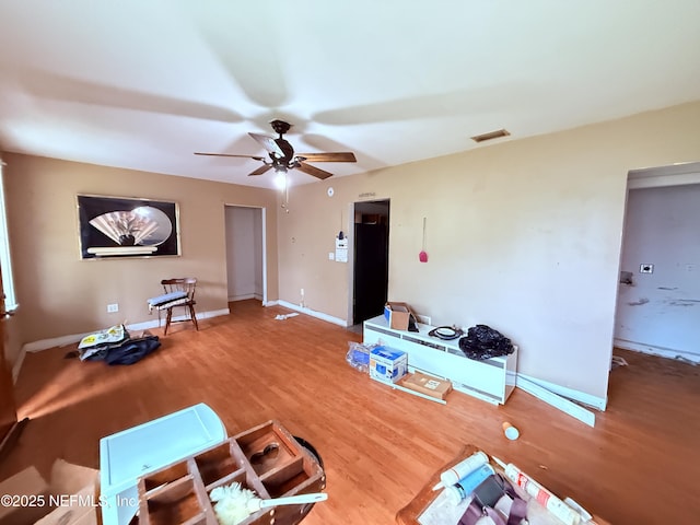 interior space with a ceiling fan, baseboards, visible vents, and wood finished floors