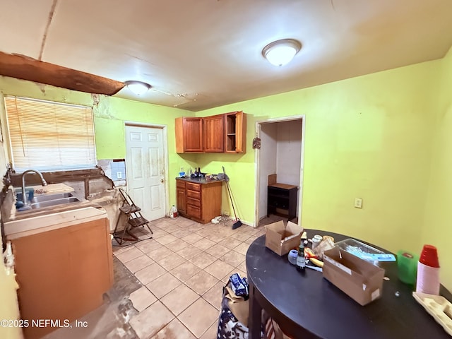 kitchen featuring brown cabinetry, light tile patterned flooring, a sink, and open shelves