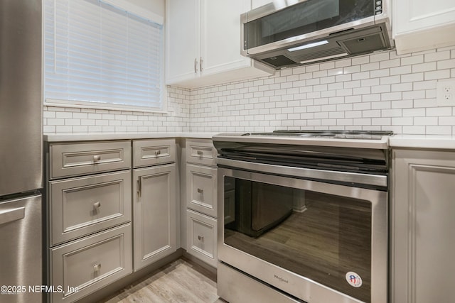 kitchen with white cabinetry, appliances with stainless steel finishes, light countertops, and backsplash