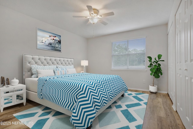 bedroom featuring a closet, wood finished floors, a ceiling fan, and baseboards