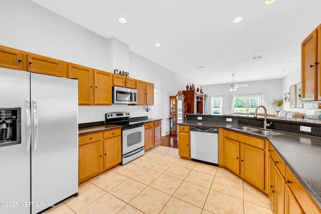 kitchen featuring recessed lighting, appliances with stainless steel finishes, brown cabinetry, and a sink
