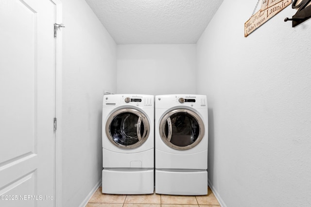 laundry area featuring laundry area, baseboards, a textured ceiling, independent washer and dryer, and light tile patterned floors