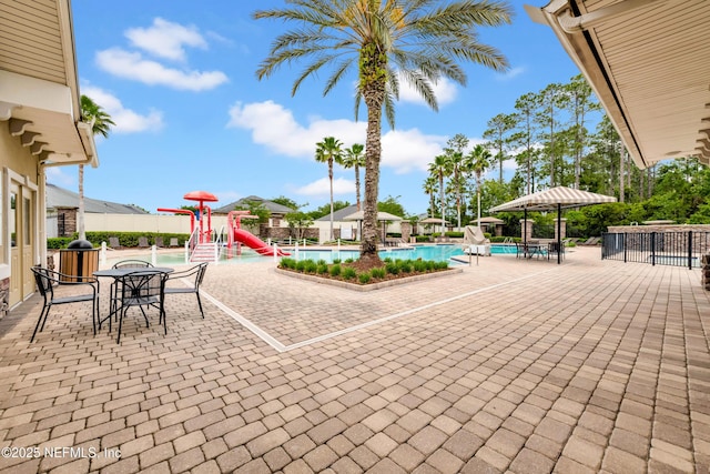 view of patio with a water play area, fence, and a community pool