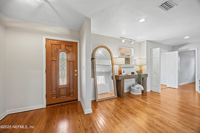 foyer entrance with visible vents, baseboards, and wood finished floors