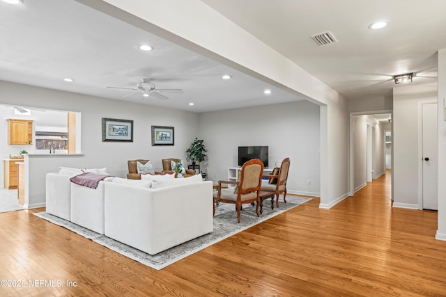 living area featuring recessed lighting, visible vents, light wood-style floors, a ceiling fan, and baseboards