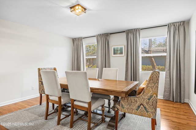 dining space featuring light wood-style flooring and baseboards