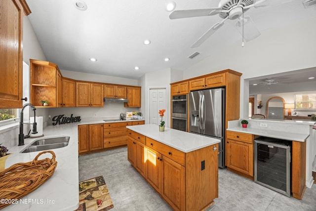 kitchen featuring wine cooler, a sink, vaulted ceiling, appliances with stainless steel finishes, and a center island