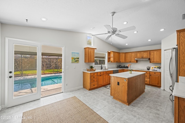 kitchen with a kitchen island, light countertops, a sink, and under cabinet range hood