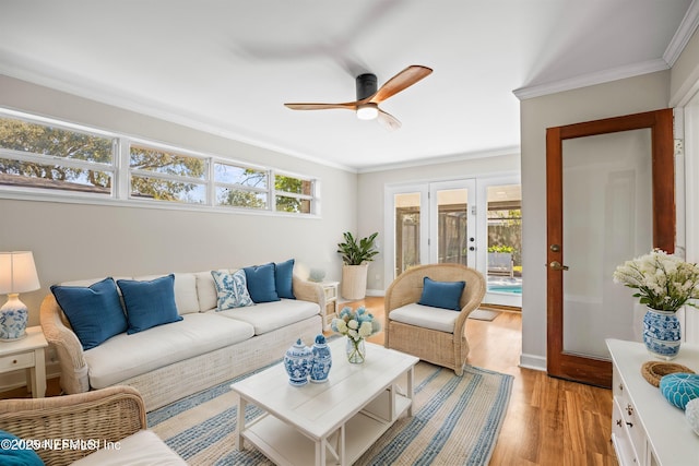 living room featuring light wood-style floors, ceiling fan, crown molding, and french doors