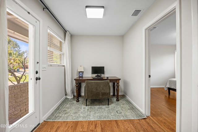 home office with baseboards, visible vents, and wood finished floors