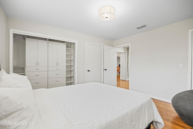 bedroom featuring visible vents, baseboards, and wood finished floors