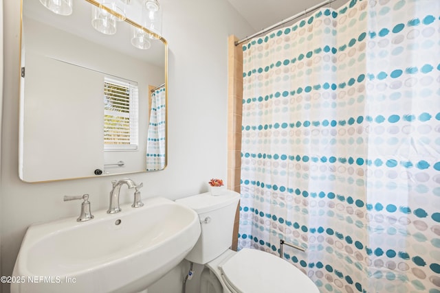 full bathroom featuring toilet, curtained shower, and a sink