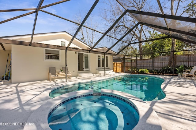 view of pool with a lanai, a patio area, a pool with connected hot tub, and fence