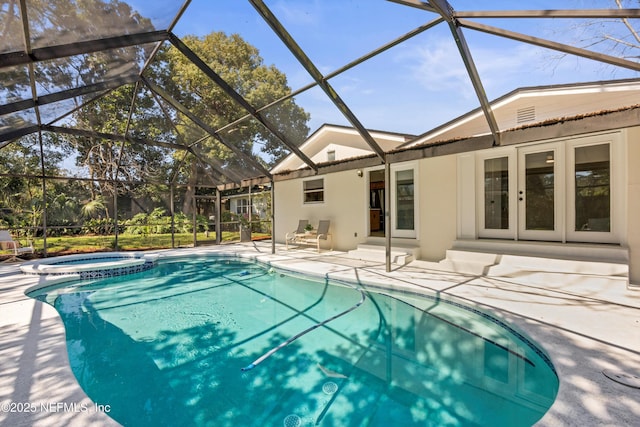 view of swimming pool featuring glass enclosure, french doors, a patio area, and a pool with connected hot tub