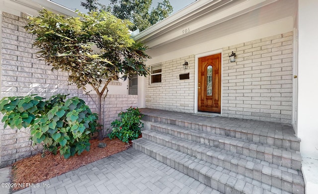 entrance to property with a porch and brick siding