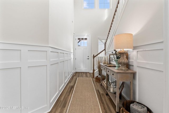 interior space with dark wood-style floors, stairway, a decorative wall, and a wealth of natural light