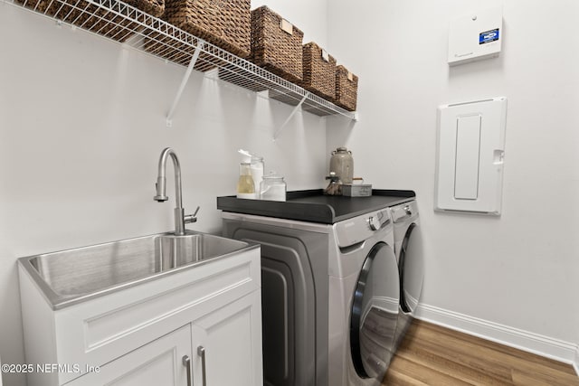 washroom with washing machine and dryer, wood finished floors, baseboards, cabinet space, and electric panel