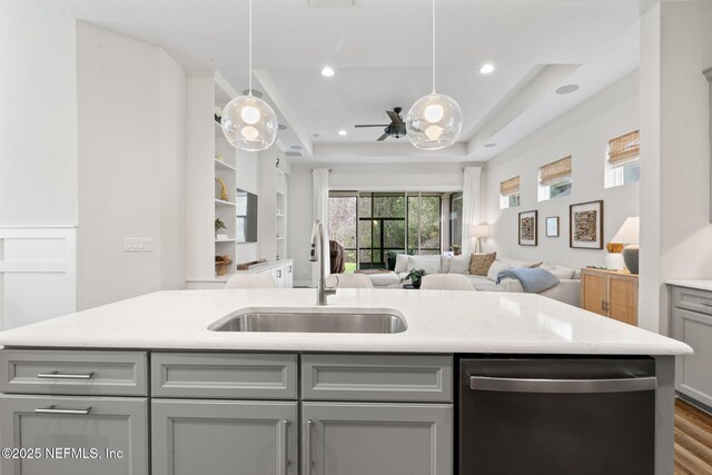 kitchen featuring a sink, open floor plan, gray cabinets, dishwasher, and a raised ceiling