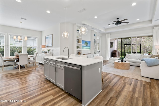 kitchen featuring light countertops, gray cabinetry, open floor plan, a sink, and dishwasher