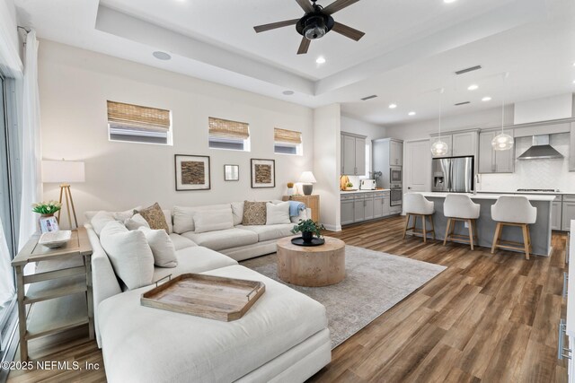 living room featuring recessed lighting, a raised ceiling, and dark wood-style flooring