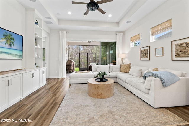 living room featuring wood finished floors, plenty of natural light, and a raised ceiling