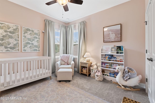 bedroom with a ceiling fan, a nursery area, and carpet