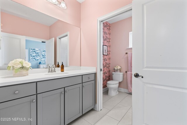 bathroom with baseboards, vanity, toilet, and tile patterned floors