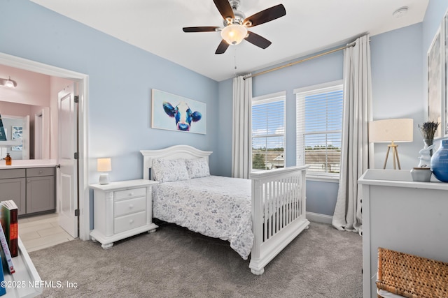 bedroom featuring light carpet, ensuite bath, and ceiling fan