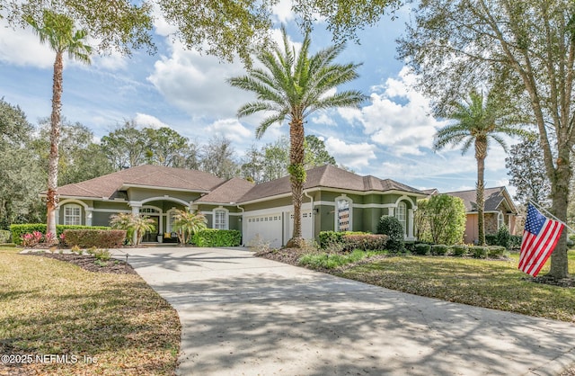 mediterranean / spanish house featuring concrete driveway, a front lawn, an attached garage, and stucco siding