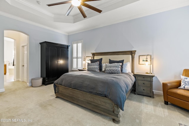 bedroom with a tray ceiling, light carpet, crown molding, and arched walkways