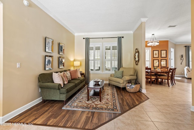 tiled living room featuring baseboards, a notable chandelier, visible vents, and crown molding