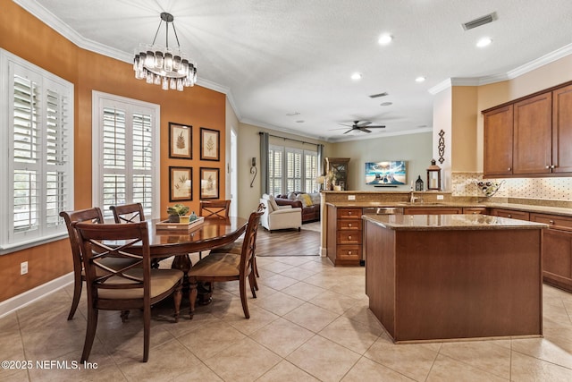 kitchen with a kitchen island, visible vents, ornamental molding, brown cabinets, and decorative backsplash