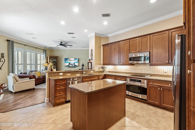 kitchen with light tile patterned floors, a peninsula, a sink, visible vents, and appliances with stainless steel finishes