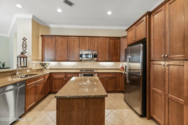 kitchen with a kitchen island, a sink, visible vents, appliances with stainless steel finishes, and dark stone counters