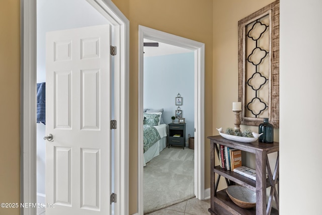 hall with light tile patterned floors and light colored carpet