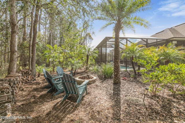 view of yard with a fire pit, glass enclosure, and an outdoor pool