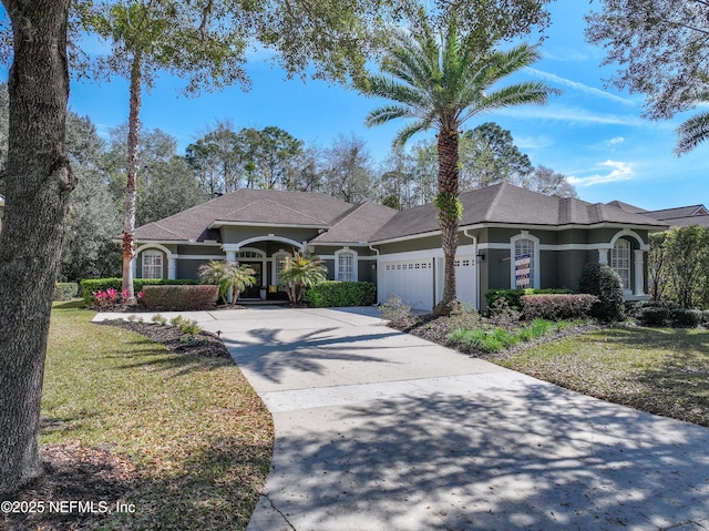 mediterranean / spanish home with a garage, driveway, a front lawn, and stucco siding