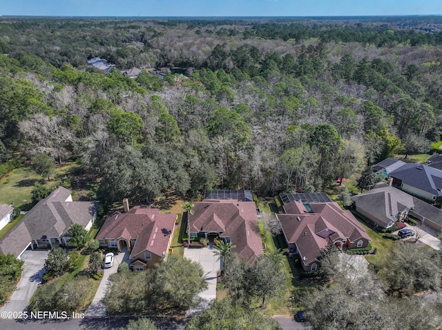 drone / aerial view featuring a wooded view and a residential view