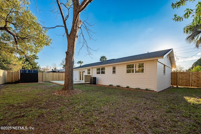 rear view of property featuring entry steps, central AC unit, a lawn, a patio, and a fenced backyard